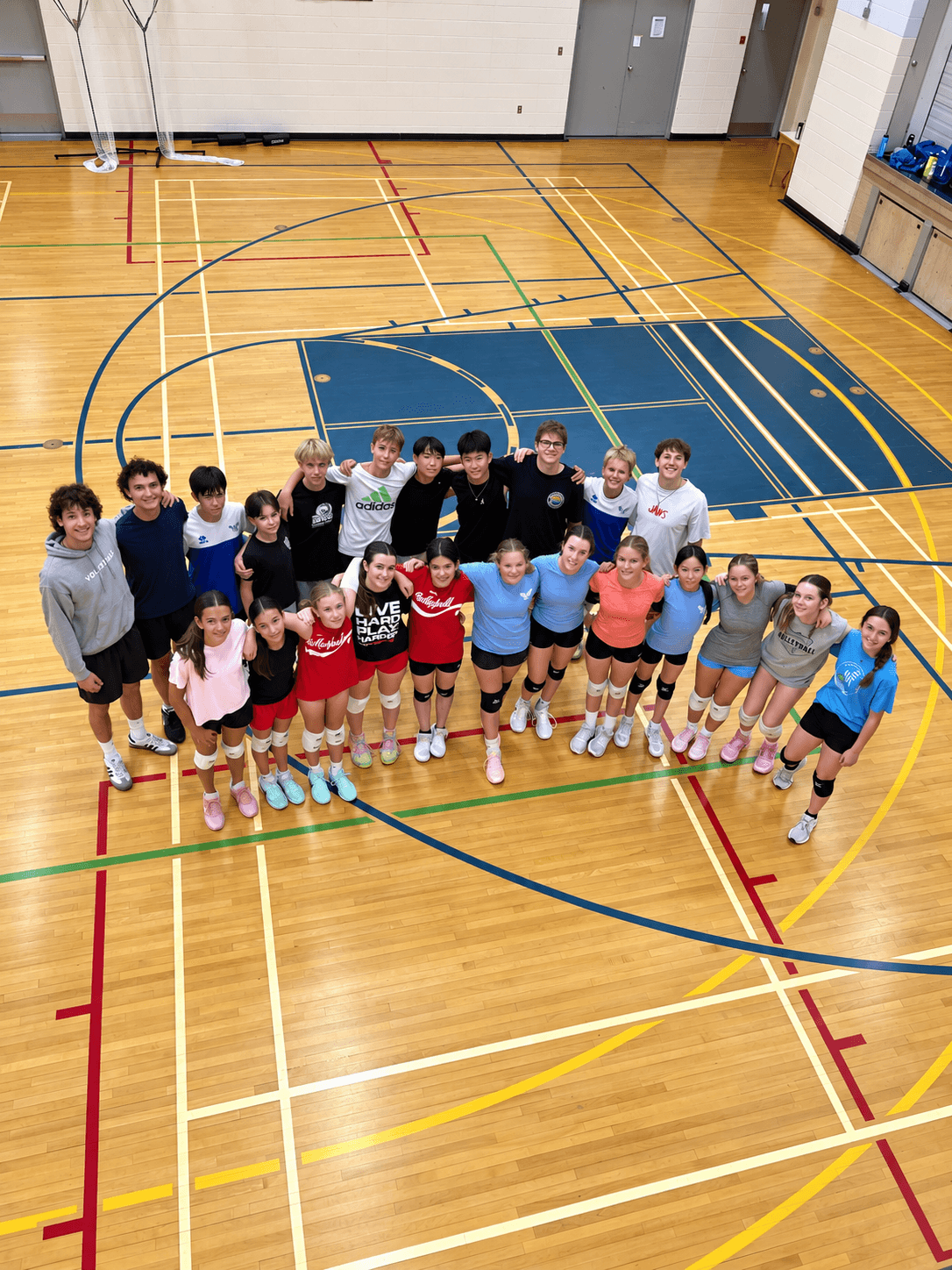 Volleyball athletes gathered for an indoor team photo on the court